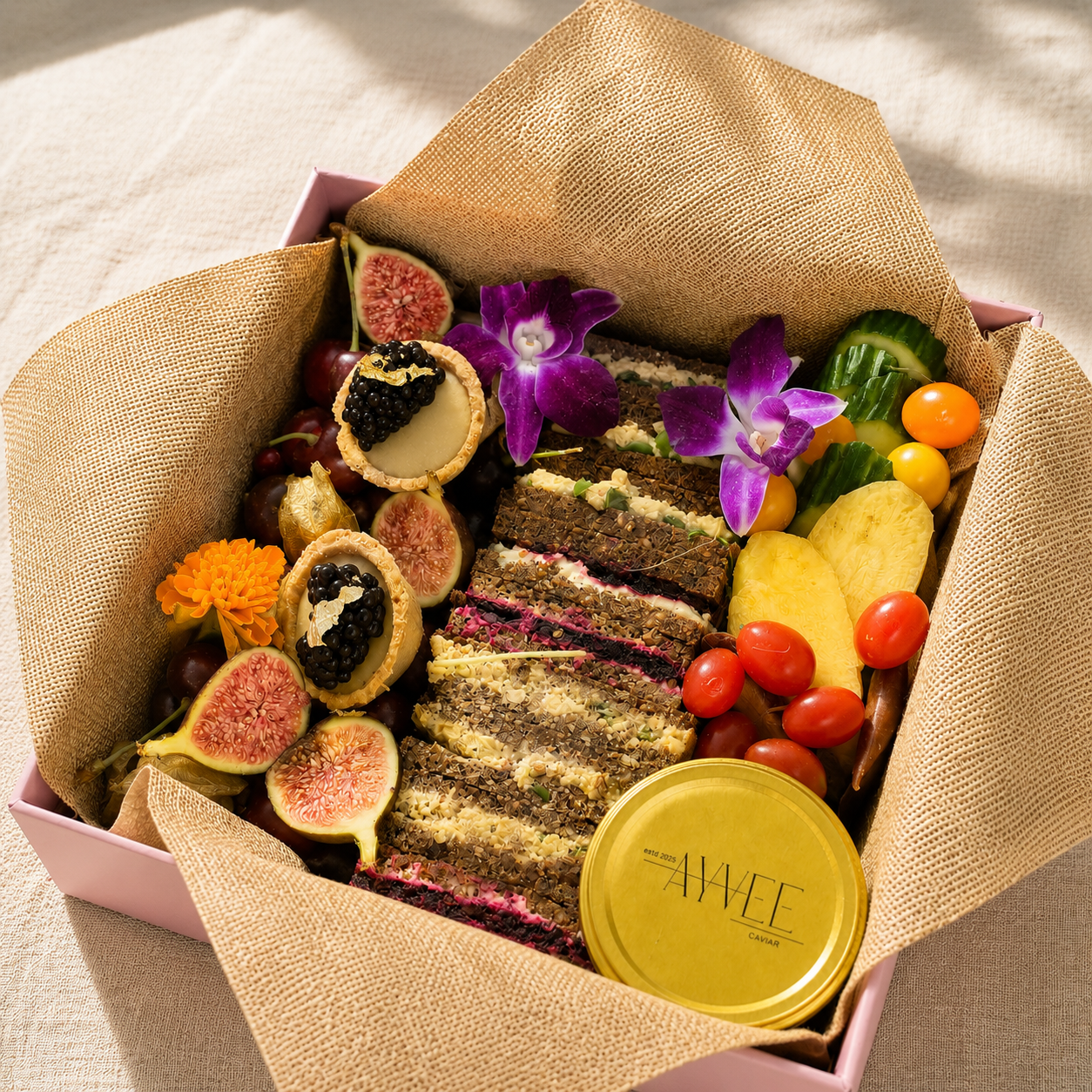 Luxury vegan grazing box with finger sandwiches, seasonal fruit, sweet treats, crudité, hummus, and Ayvee Caviar served with crackers in elegant natural lighting.