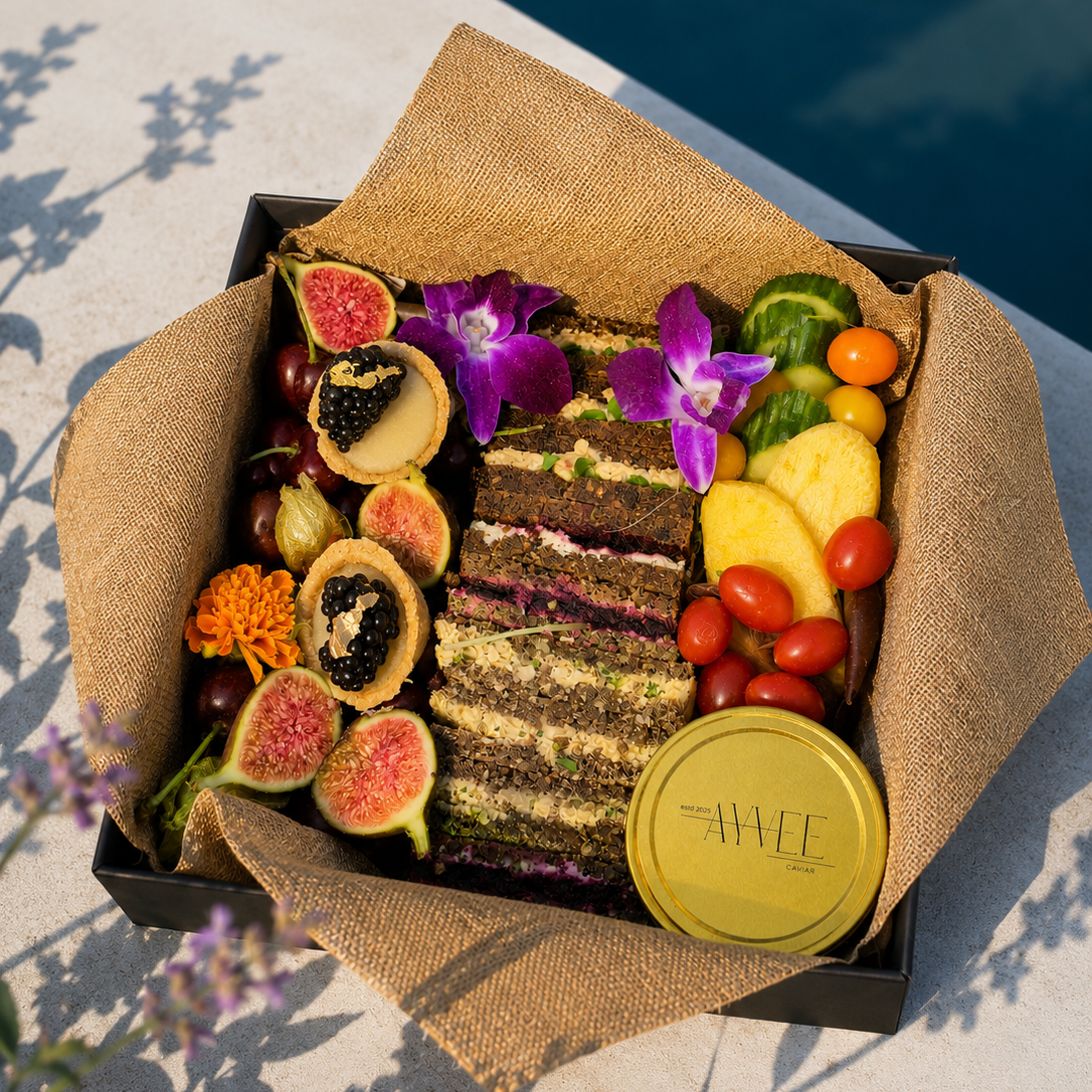 Assorted fruits, vegetables, and a cake in a decorative box with a yellow lid on a light surface.