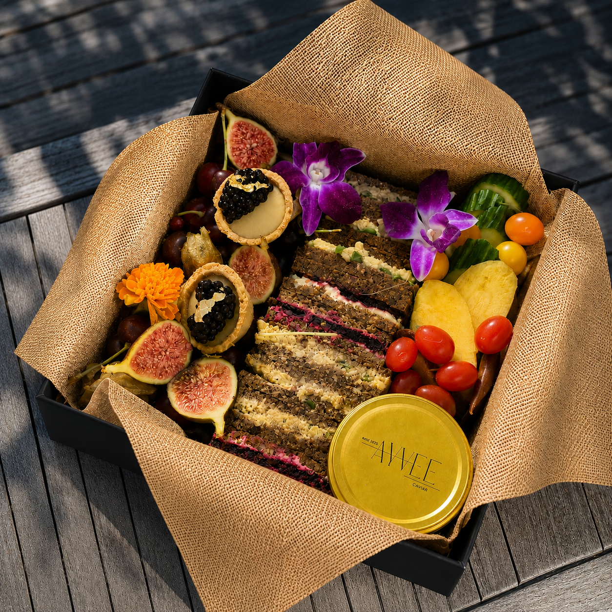Gourmet food platter with cake, fruits, and flowers on a wooden surface